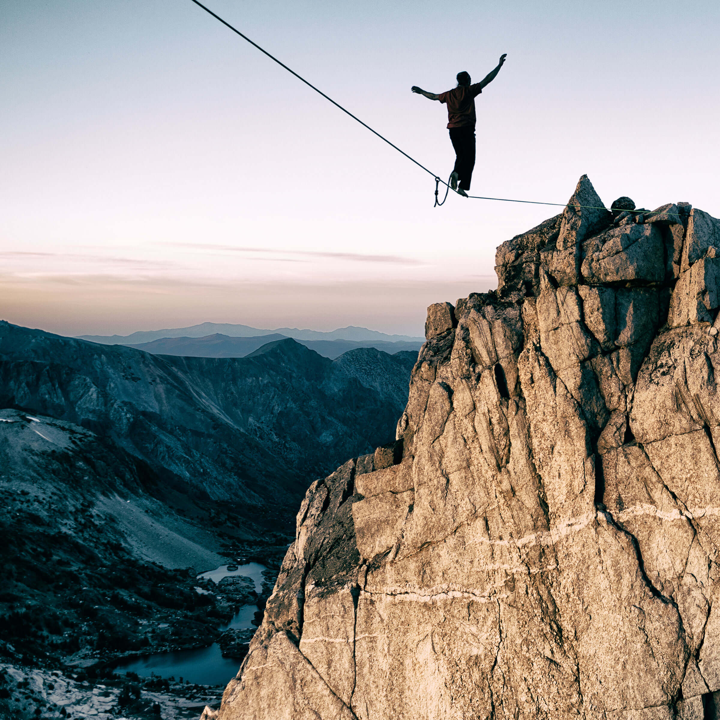 Ein Akrobat balanciert auf einem Seil von einer Bergspitze zur anderen.